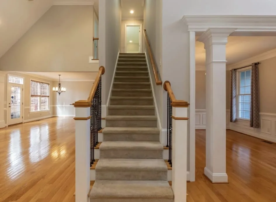 Carpeted staircase with black metal spindles and surrounding hardwood
